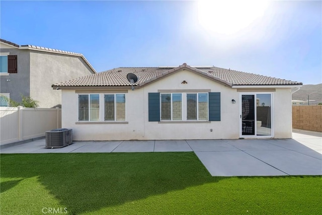 back of property with central AC unit, a patio, and a lawn