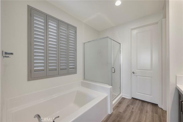 bathroom with wood-type flooring, shower with separate bathtub, and vanity