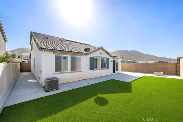 rear view of house featuring a mountain view, a yard, a patio area, and central air condition unit