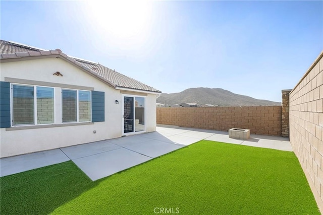 back of property with a mountain view, a yard, and a patio