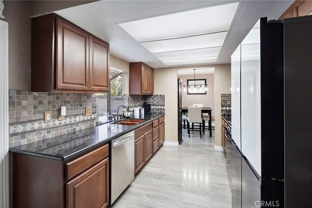 kitchen with sink, tasteful backsplash, light hardwood / wood-style flooring, stainless steel dishwasher, and pendant lighting