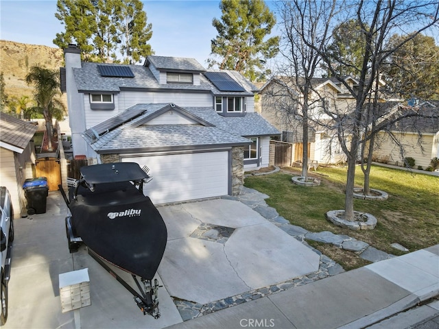 view of front of home with a garage, a front lawn, and solar panels