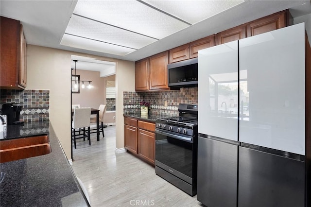 kitchen featuring sink, black range with gas cooktop, white fridge, decorative backsplash, and light wood-type flooring