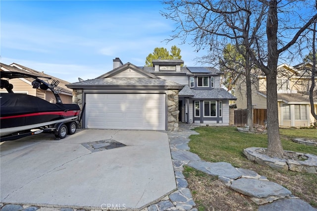 view of front facade with a garage, a front yard, and solar panels