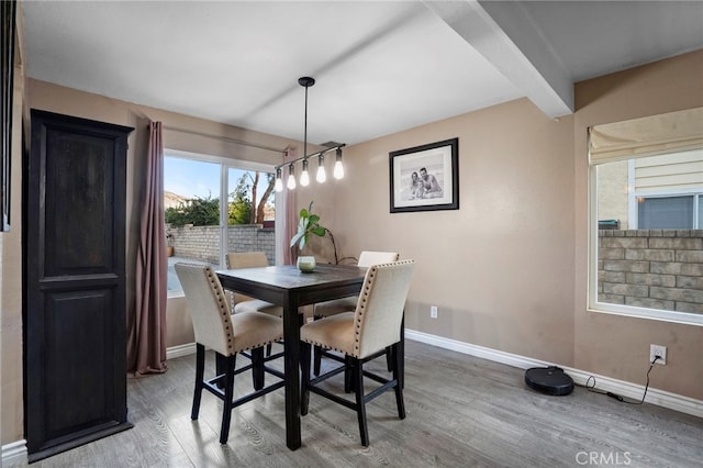 dining space with beam ceiling and hardwood / wood-style floors