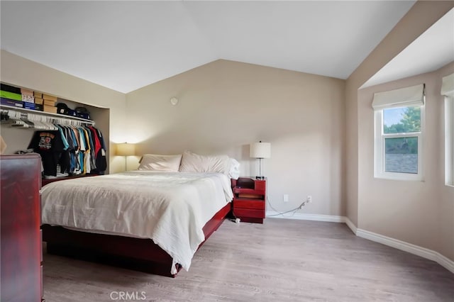 bedroom featuring vaulted ceiling, a closet, and light wood-type flooring