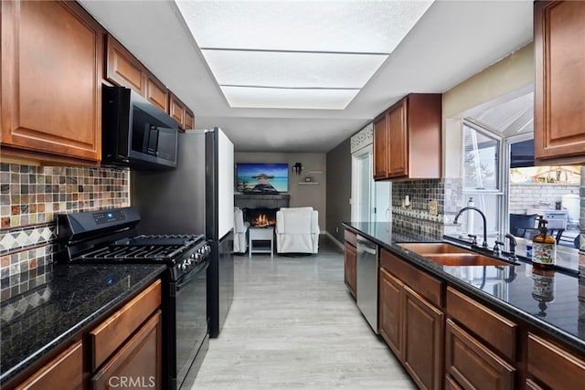 kitchen with sink, black range with gas cooktop, backsplash, stainless steel dishwasher, and light wood-type flooring