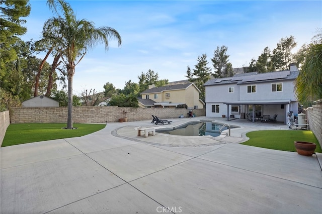 exterior space with a yard, a fenced in pool, a patio, and solar panels