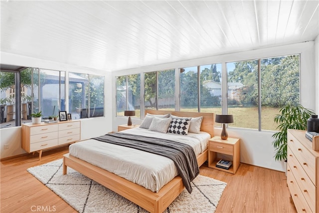 bedroom with multiple windows, wooden ceiling, and light wood-type flooring