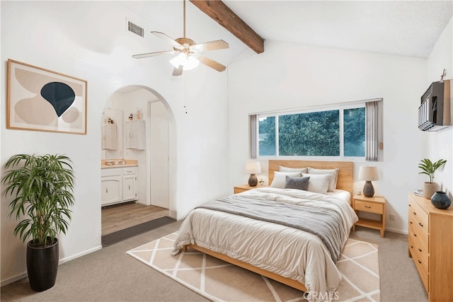 carpeted bedroom featuring ceiling fan, lofted ceiling with beams, ensuite bath, and an AC wall unit