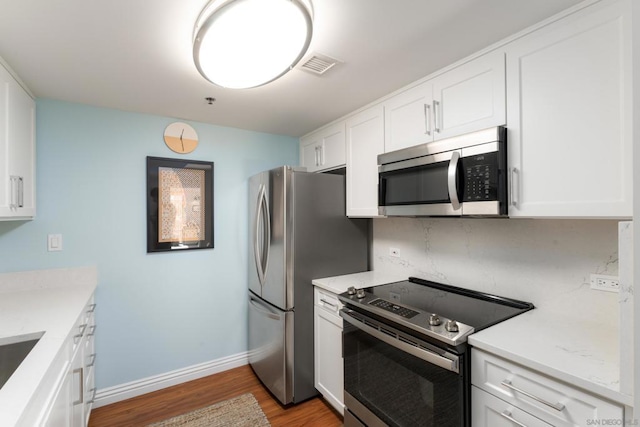 kitchen with stainless steel appliances, light hardwood / wood-style flooring, and white cabinets