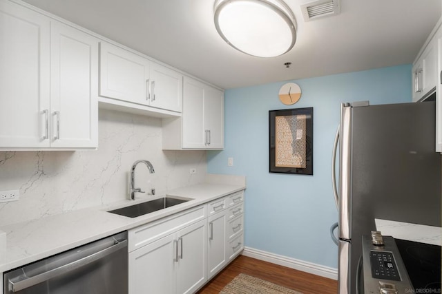 kitchen with appliances with stainless steel finishes, dark hardwood / wood-style floors, tasteful backsplash, white cabinetry, and sink