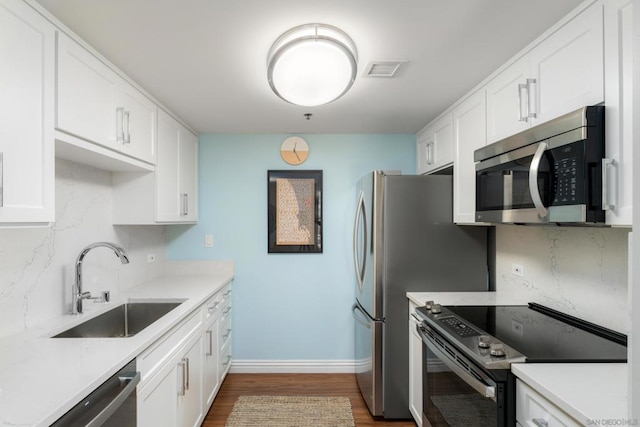 kitchen featuring appliances with stainless steel finishes, sink, white cabinets, and decorative backsplash