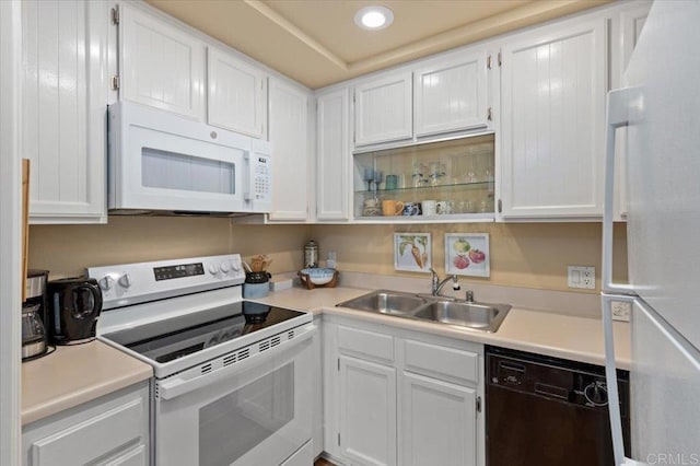 kitchen with white appliances, sink, and white cabinets