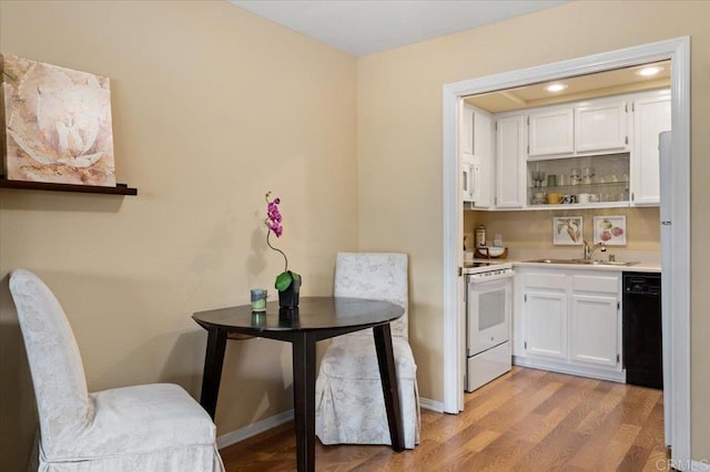 interior space with sink, white appliances, white cabinets, and light wood-type flooring