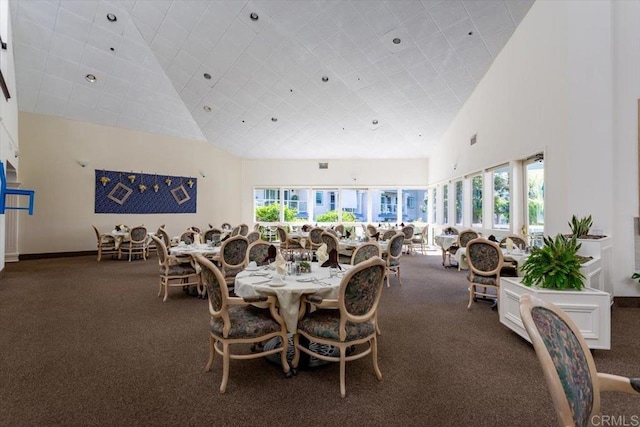 dining room featuring a healthy amount of sunlight, high vaulted ceiling, and dark colored carpet