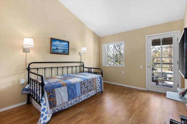 bedroom featuring hardwood / wood-style flooring, lofted ceiling, multiple windows, and access to outside