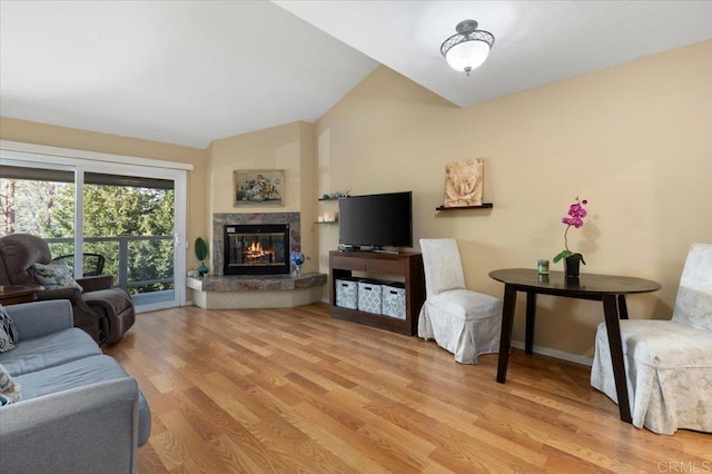 living room with lofted ceiling, a fireplace, and light hardwood / wood-style floors