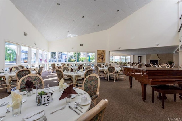 dining area featuring carpet, a healthy amount of sunlight, and high vaulted ceiling