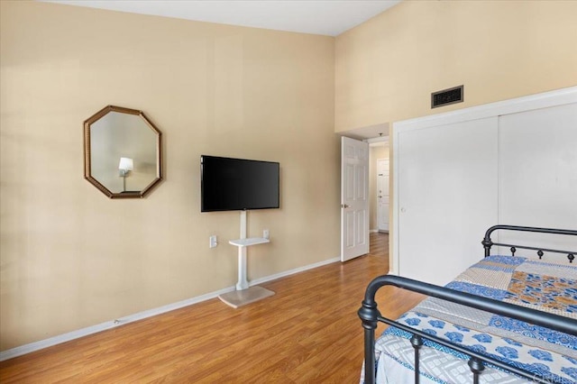 bedroom featuring a towering ceiling, wood-type flooring, and a closet