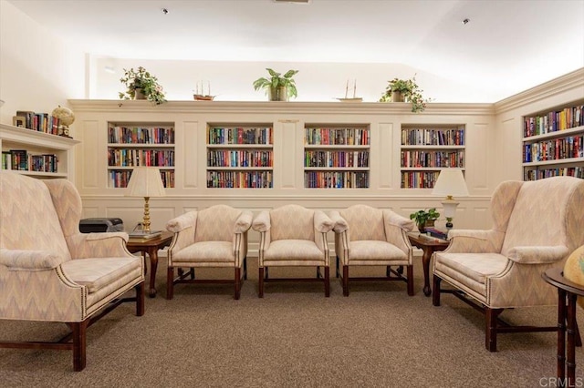 living area featuring built in shelves, lofted ceiling, and dark colored carpet