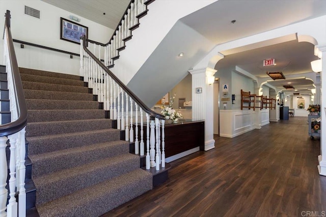 stairway featuring hardwood / wood-style flooring and ornate columns