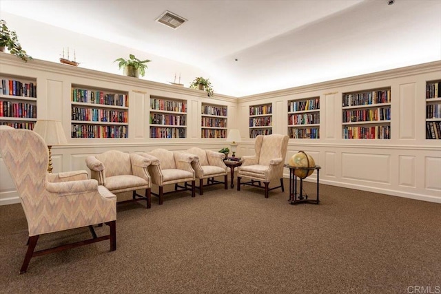 sitting room featuring lofted ceiling, built in features, and dark carpet