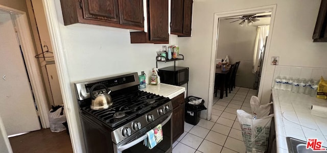 kitchen featuring dark brown cabinetry, stainless steel range with gas cooktop, ceiling fan, and light tile patterned flooring