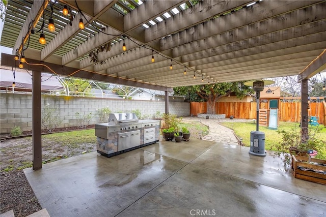 view of patio featuring a playground, an outdoor kitchen, and a pergola