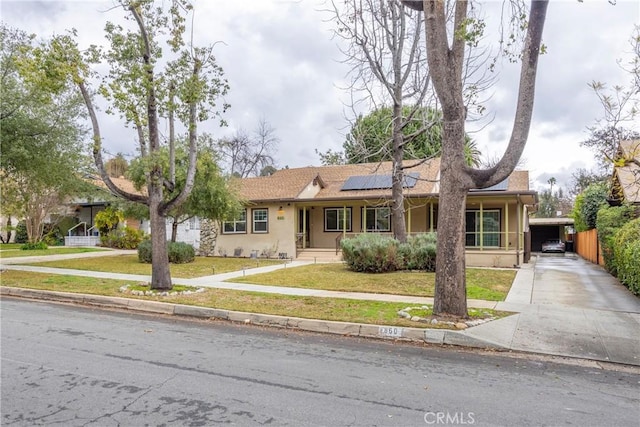 single story home featuring a carport, a front yard, and solar panels