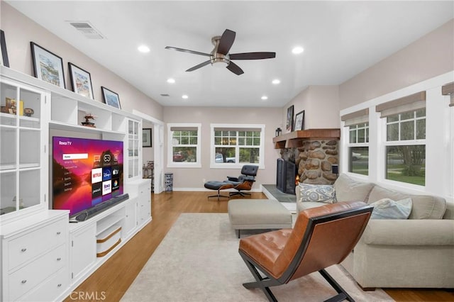 living room featuring ceiling fan, a fireplace, and light hardwood / wood-style floors