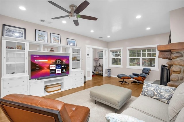 living room with ceiling fan, a fireplace, and light hardwood / wood-style flooring