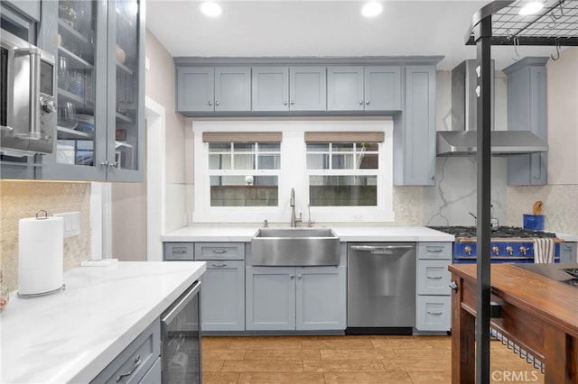 kitchen featuring sink, tasteful backsplash, appliances with stainless steel finishes, beverage cooler, and wall chimney range hood