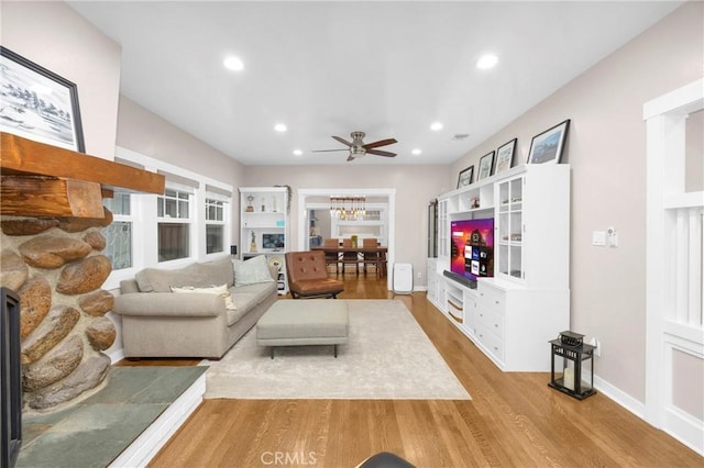 living room featuring ceiling fan, a fireplace, and light wood-type flooring