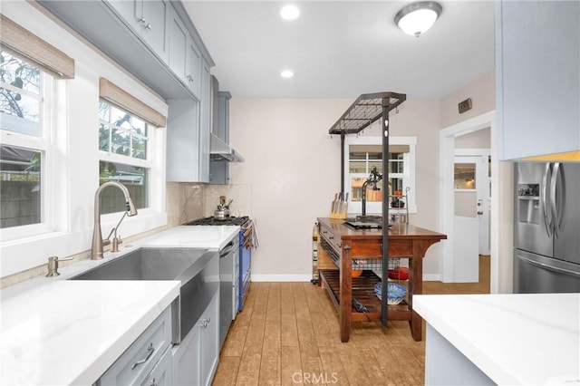 kitchen featuring gray cabinets, sink, decorative backsplash, stainless steel appliances, and light hardwood / wood-style flooring