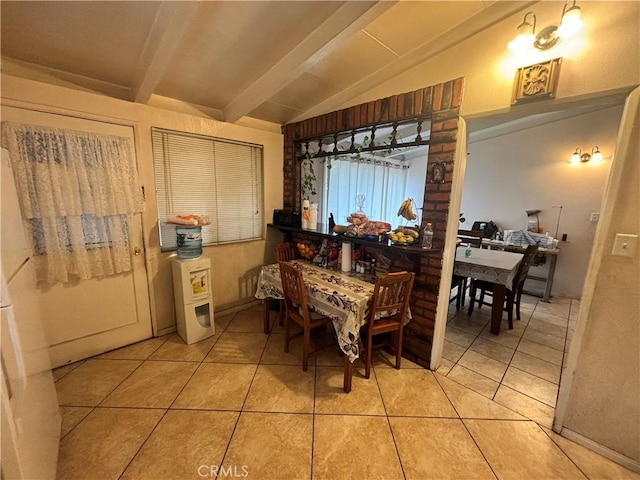 tiled dining room featuring lofted ceiling with beams