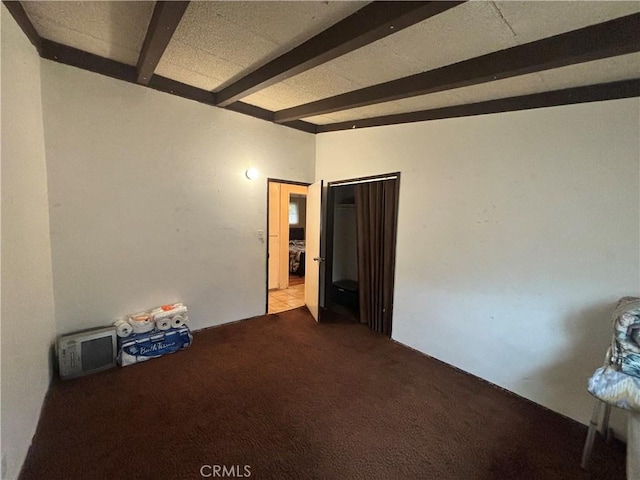 spare room featuring carpet and vaulted ceiling with beams