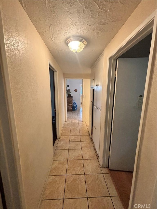 hallway featuring light tile patterned floors and a textured ceiling