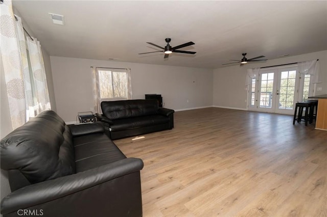 living room featuring ceiling fan, plenty of natural light, light hardwood / wood-style floors, and french doors