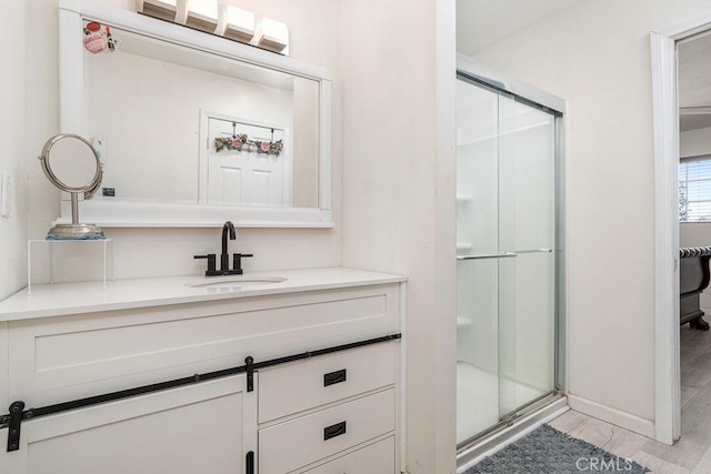 bathroom with hardwood / wood-style flooring, vanity, and a shower with shower door