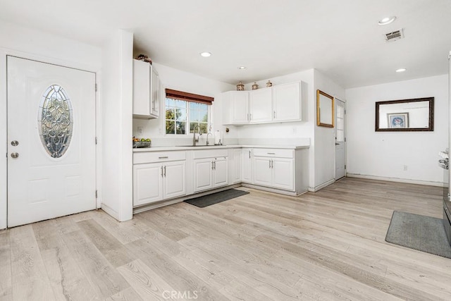 kitchen featuring sink, white cabinets, and light wood-type flooring