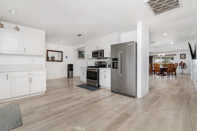 kitchen featuring white cabinetry, a notable chandelier, light hardwood / wood-style flooring, and appliances with stainless steel finishes