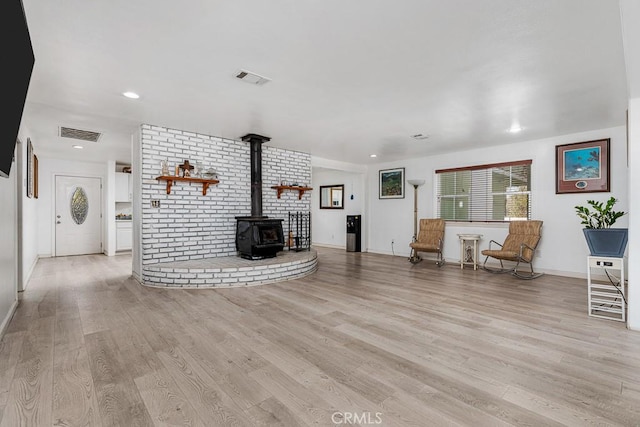 unfurnished living room featuring a wood stove and light wood-type flooring