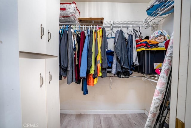 walk in closet with light hardwood / wood-style floors