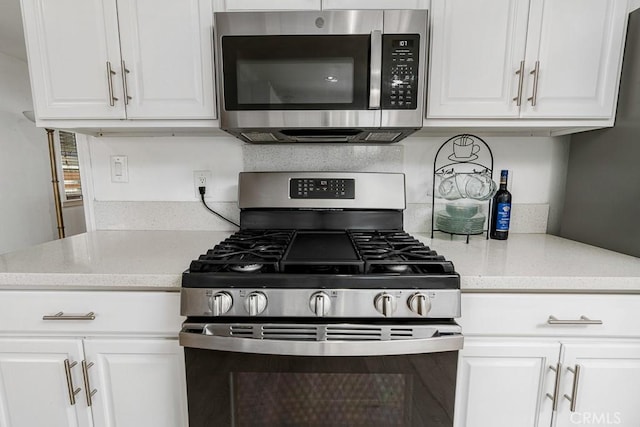 kitchen with white cabinetry, stainless steel appliances, and light stone countertops