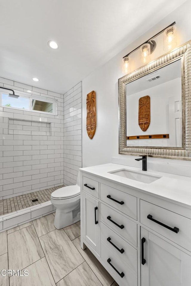 bathroom with toilet, recessed lighting, vanity, visible vents, and a tile shower