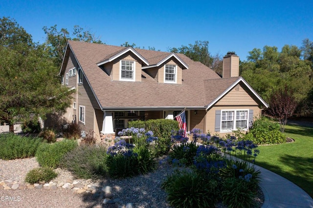 view of front of property with a shingled roof, a chimney, and a front yard