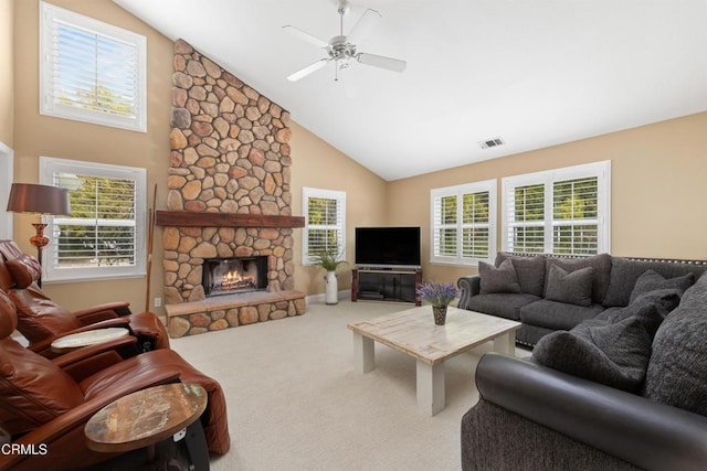 living room featuring a healthy amount of sunlight, visible vents, a stone fireplace, and carpet flooring