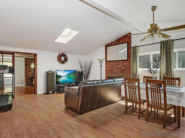 living room with lofted ceiling with skylight, ceiling fan, and light hardwood / wood-style floors