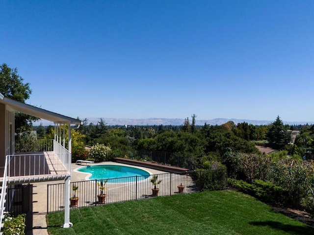 view of pool featuring a lawn and a diving board